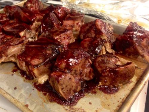 A tray of glazed, cooked meat pieces, glistening with a rich, dark sauce.