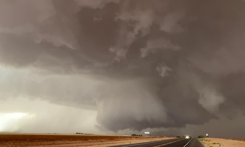 Dark, ominous storm clouds loom over a deserted road, hinting at an approaching storm.