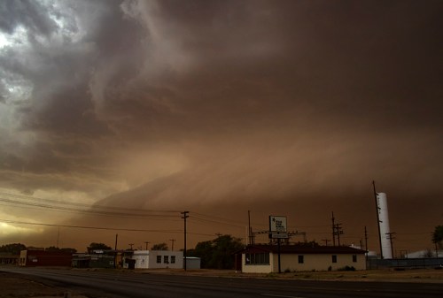 A dramatic sky filled with dark clouds looms over a small town, hinting at an approaching storm.