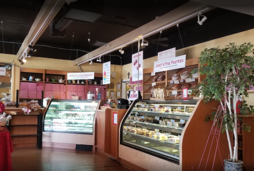 Interior of a bakery featuring display cases with pastries, a counter, and decorative signage.