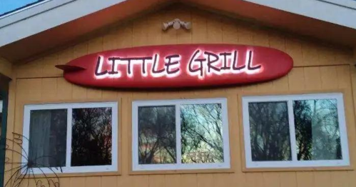 Sign for "Little Grill" on a yellow building with a surfboard design above the windows.