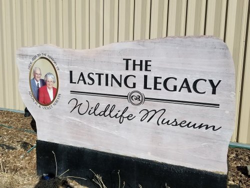 Sign for "The Lasting Legacy Wildlife Museum" featuring a photo of a couple.