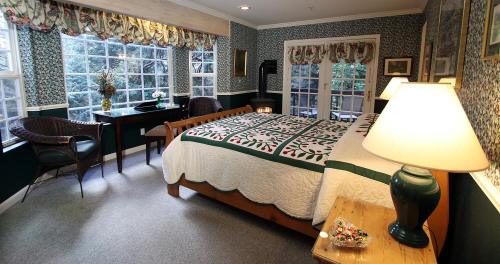Cozy bedroom with a quilted bed, patterned wallpaper, and large windows overlooking greenery.