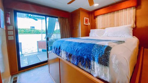 Cozy bedroom with a large bed, blue throw blanket, and sliding glass door leading to a scenic outdoor view.