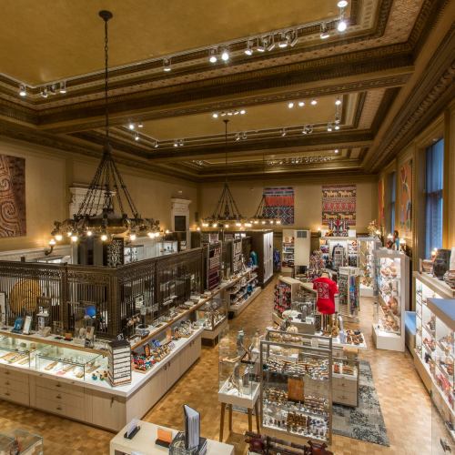 A spacious museum shop filled with various artifacts, displays, and decorative lighting under a high ceiling.