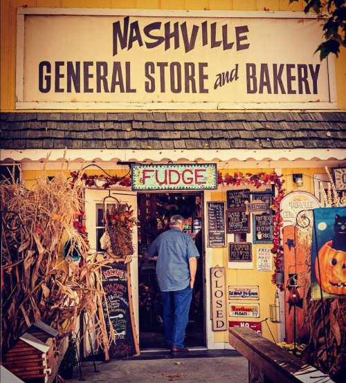 A man enters the Nashville General Store and Bakery, decorated with autumn leaves and signs, including "Fudge."