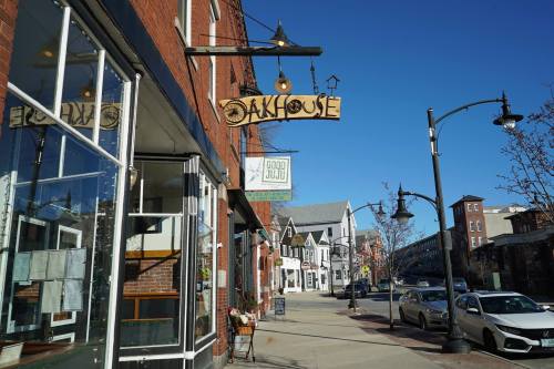A street view featuring a restaurant sign reading "Oakhouse" and nearby shops, with clear blue skies above.