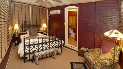 Cozy bedroom with a wrought iron bed, leopard print accents, and a doorway leading to a bathroom. Warm lighting.