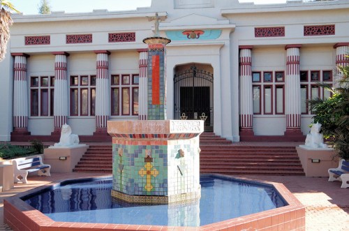 A decorative fountain with colorful tiles in front of a historic building featuring columns and ornate details.