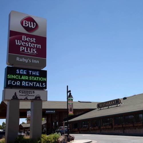 Sign for Best Western Plus Ruby's Inn with a restaurant and arrival area visible in the background. Clear blue sky.