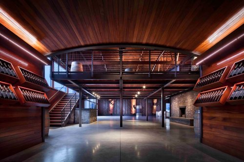 Modern winery interior featuring wooden beams, wine racks, and a spacious, open layout with industrial design elements.