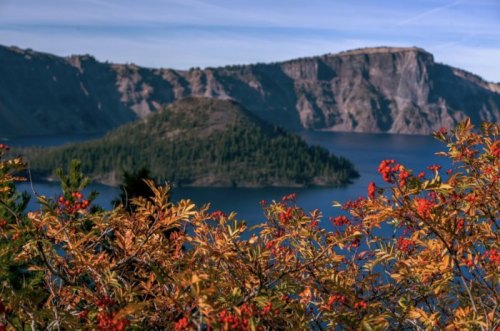 A scenic view of a lake surrounded by cliffs, with vibrant autumn foliage in the foreground.
