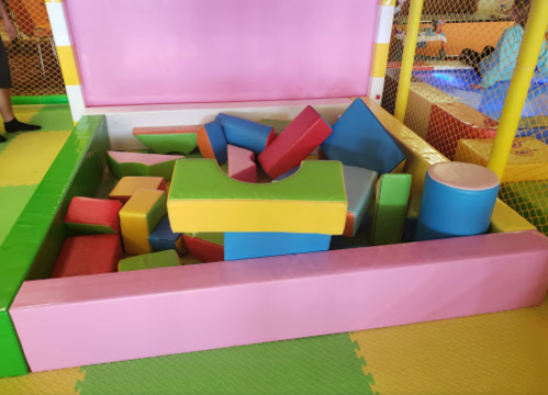 A colorful play area filled with various foam blocks in different shapes and sizes, surrounded by soft flooring.