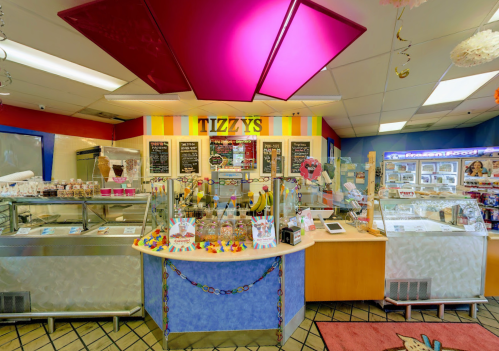 Colorful ice cream shop interior with a service counter, menu boards, and vibrant decorations.