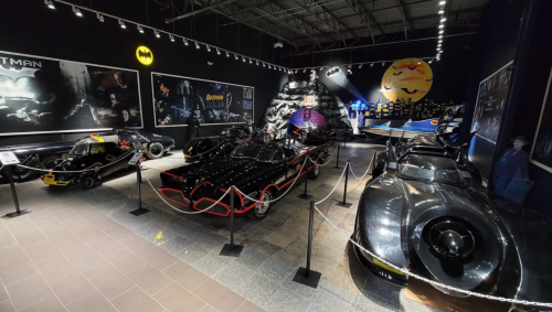 A display of various Batmobiles from different Batman films in a themed exhibition.