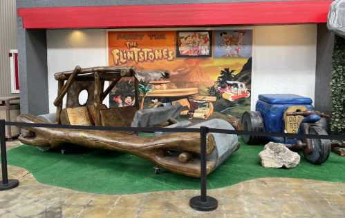 A wooden car inspired by "The Flintstones" displayed in a themed setting with a colorful backdrop.
