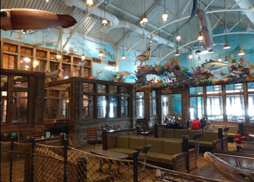 Interior of a seafood restaurant featuring nautical decor, wooden furnishings, and colorful fish murals on the walls.
