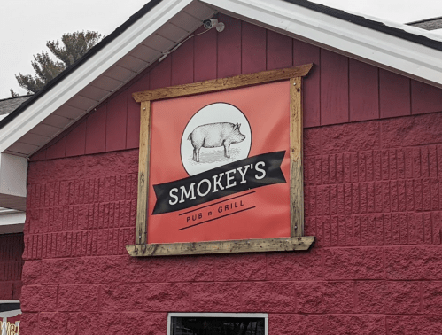 Sign for Smokey's Pub n' Grill featuring a pig illustration on a red background.