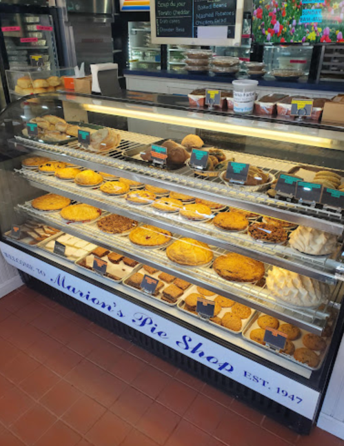 A display case filled with various pies and baked goods at Marion's Pie Shop, showcasing a variety of desserts.