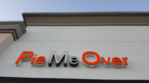 Sign for "Pie Me Over" in orange and black letters against a clear sky.