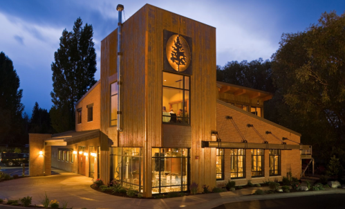 A modern building with a wooden facade and large windows, set against a twilight sky.