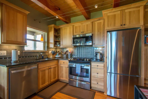 A modern kitchen with wooden cabinets, stainless steel appliances, and a cozy, well-lit atmosphere.