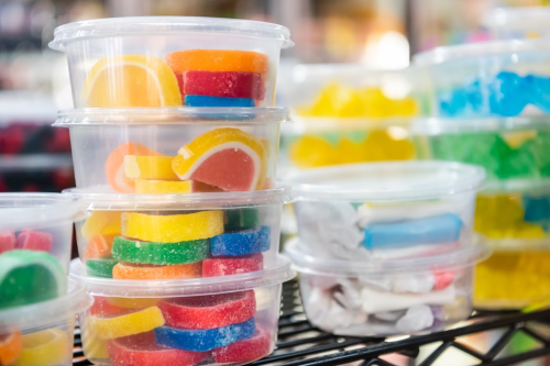 Colorful gummy candies stacked in clear containers on a shelf, featuring various shapes and vibrant hues.