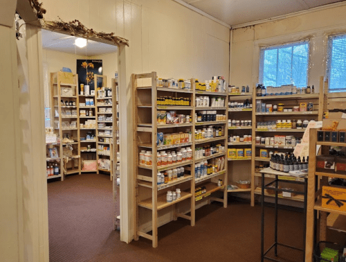 A cozy shop interior with wooden shelves filled with various health products and supplements. Natural light from windows.