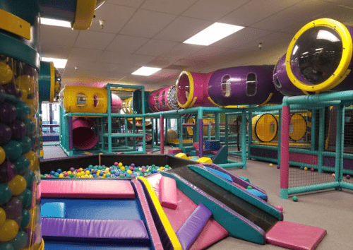 Colorful indoor play area with slides, ball pits, and climbing structures for children.