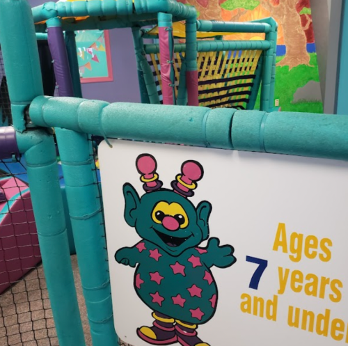 Colorful play structure with a sign for children ages 7 and under, featuring a cartoon character with big ears.