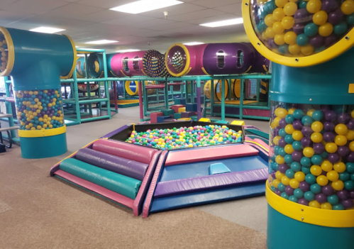 Colorful indoor play area featuring ball pits and tunnels filled with plastic balls. Fun and vibrant atmosphere for kids.