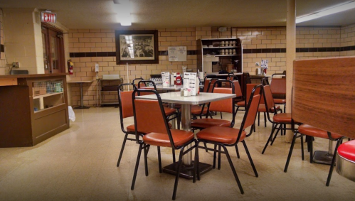 A cozy diner interior with empty tables and chairs, featuring a vintage decor and warm lighting.