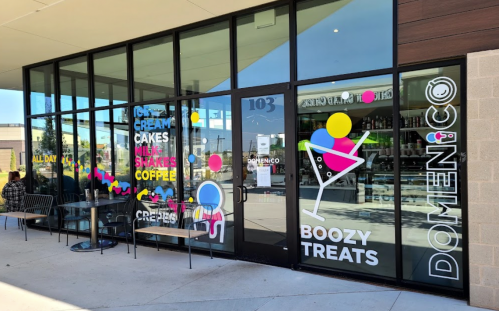 Exterior of Domenico, featuring colorful signage for ice cream, cakes, and boozy treats, with outdoor seating.