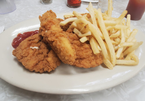 A plate of crispy fried chicken pieces served with French fries and a side of ketchup.