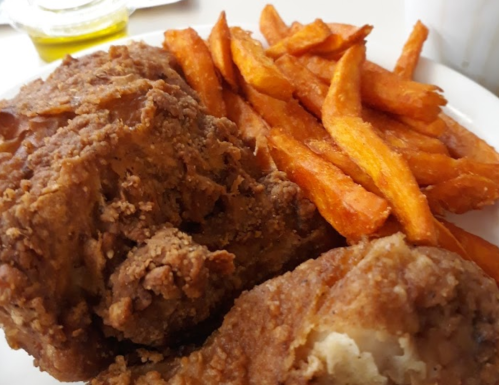 A plate of crispy fried chicken served with golden sweet potato fries.