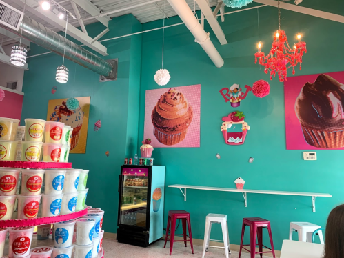 Colorful ice cream shop interior with cupcake art, a stacked ice cream display, and bright decor.