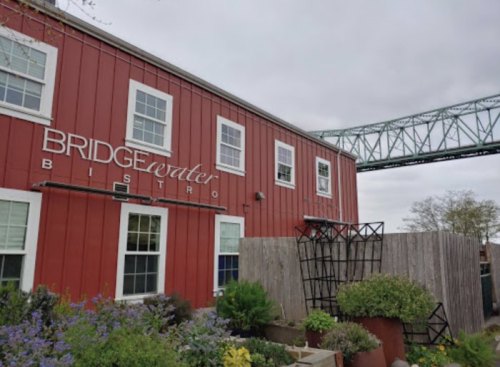 A red bistro building with the sign "Bridgewater Bistro" and a bridge in the background, surrounded by greenery.