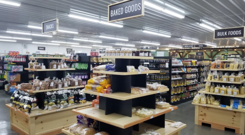 A grocery store interior featuring shelves of baked goods, snacks, and bulk foods in a well-organized layout.