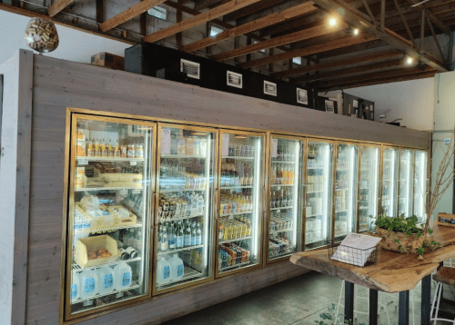 A well-stocked refrigerator display in a store, featuring various beverages and snacks behind glass doors.