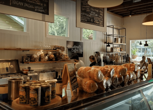 A cozy coffee shop interior with a counter displaying baked goods and drinks, and staff preparing orders.