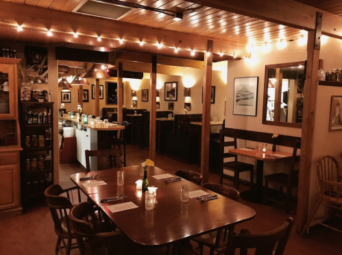 Cozy restaurant interior with wooden tables, soft lighting, and decorative wall art, creating an inviting atmosphere.