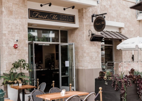 Exterior of Frost Me Cafe & Bakery, featuring outdoor seating and a welcoming entrance with plants.