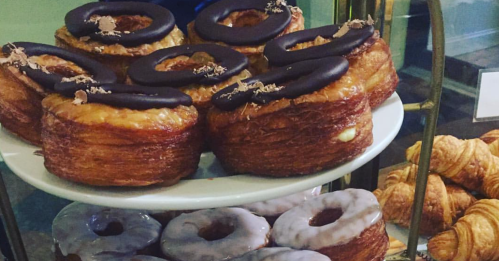 A display of pastries featuring chocolate-topped croissants and glazed donuts on a white plate.