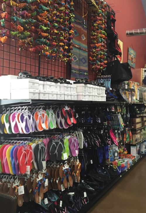 A colorful display of flip-flops and accessories on shelves, with vibrant decorations hanging above.