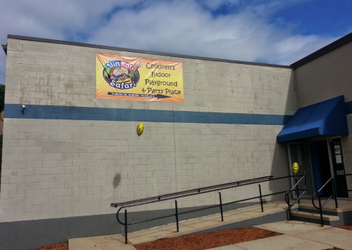 A building exterior with a banner reading "Kimi Kari's Safari: Children's Indoor Playground & Party Place."