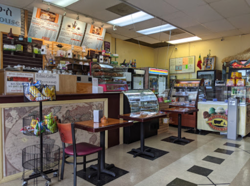 A cozy café interior with a display case, tables, and a counter filled with snacks and beverages.