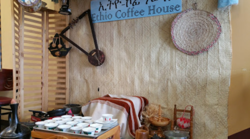 A cozy Ethio Coffee House setup with traditional decor, coffee cups, and cultural artifacts on display.