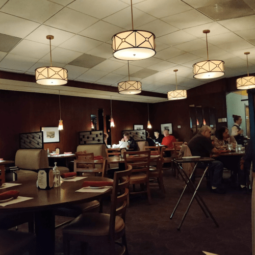 A cozy restaurant interior with wooden tables, warm lighting, and diners enjoying their meals.