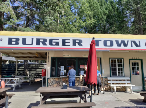 A burger stand named "Burger Town" with outdoor seating and customers ordering at the counter, surrounded by trees.