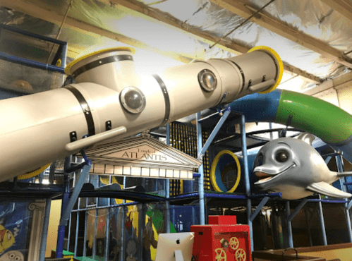 Colorful indoor play structure featuring slides, tunnels, and a large fish sculpture.